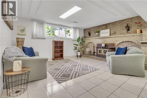 Spacious room featuring a stone-clad fireplace with a hearth, light-toned tile flooring, and white painted walls - 2344 Brinell Avenue, Burlington, ON - Indoor With Fireplace