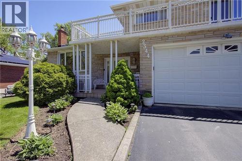 Stone veneer exterior with an integrated garage, upper-level balcony, and a paved driveway - 2344 Brinell Avenue, Burlington, ON - Outdoor With Balcony