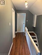 Hall with dark wood-style flooring, an upstairs landing, and vaulted ceiling - 