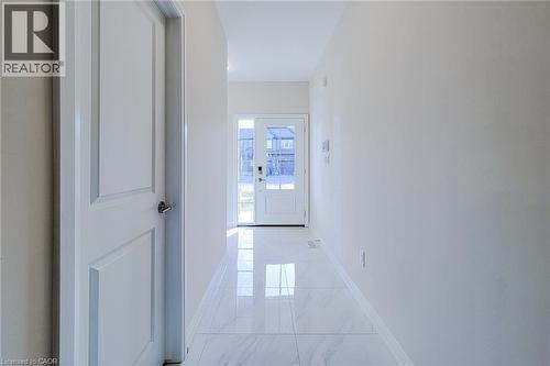 Bright entryway featuring large format polished tile flooring, a white paneled door with chrome hardware, and a glass-paneled front door - 111 Alicia Crescent, Thorold, ON 
