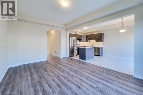 Expansive living area featuring wood-finish flooring, a kitchen with dark cabinetry, stainless steel appliances, a center island, and recessed lighting - 111 Alicia Crescent, Thorold, ON 