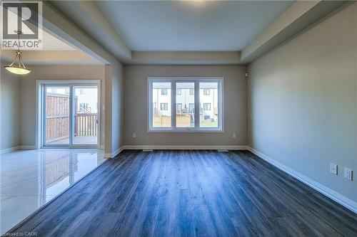 Spacious interior featuring a combination of wood-finish flooring and reflective tile, a tray ceiling, and a large window providing ample natural light - 111 Alicia Crescent, Thorold, ON 