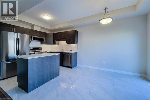 Kitchen featuring dark wood-finish cabinetry, stainless steel appliances, and a central island with a light-toned countertop - 111 Alicia Crescent, Thorold, ON 