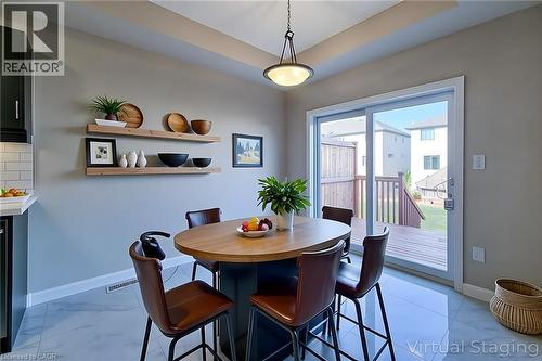 Dining area featuring a wood-top island, sleek bar stools, and a contemporary pendant light fixture - 111 Alicia Crescent, Thorold, ON 