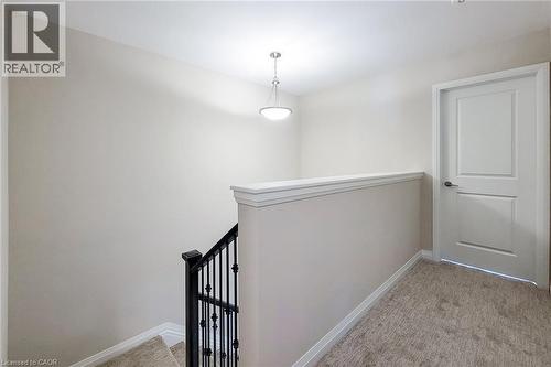 Upper landing featuring plush carpeting, a suspended light fixture, and a white panel door - 111 Alicia Crescent, Thorold, ON 