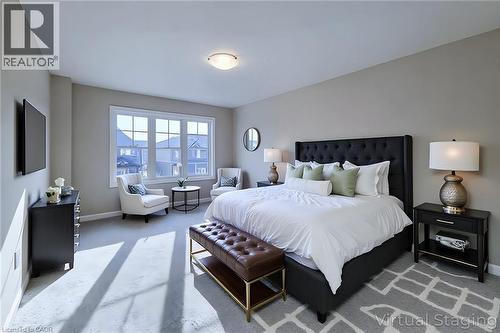 Spacious bedroom featuring light neutral wall tones, plush gray carpeting, a large multipane window, and a flush-mount ceiling light fixture - 111 Alicia Crescent, Thorold, ON 
