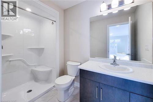 Full bathroom featuring a walk-in shower with built-in seating and grab bar, a single vanity with dark wood-finish cabinetry, a white countertop, and a large wall-mounted mirror - 111 Alicia Crescent, Thorold, ON 