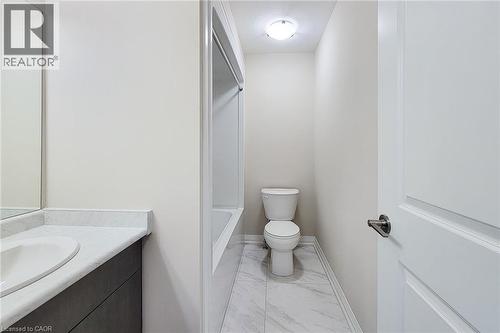 Bathroom featuring a vanity with an integrated sink and light-toned countertop, a bathtub with a shower surround, a toilet, and light-toned floor tiling - 111 Alicia Crescent, Thorold, ON 