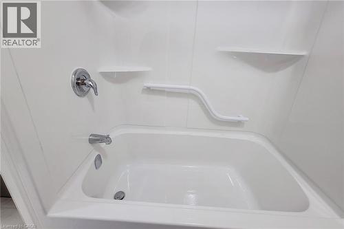White tub and shower combination with chrome fixtures, integrated shelving, and a safety grab bar - 111 Alicia Crescent, Thorold, ON 