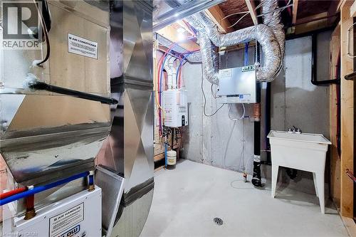 Utility area featuring a water heater, air handler, extensive ductwork, and a utility sink - 111 Alicia Crescent, Thorold, ON 