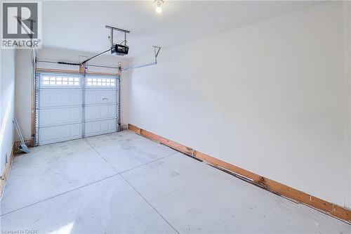 Single-bay garage featuring a concrete floor, white walls, an automatic overhead door opener, and a panel-style garage door with upper window inserts - 111 Alicia Crescent, Thorold, ON 