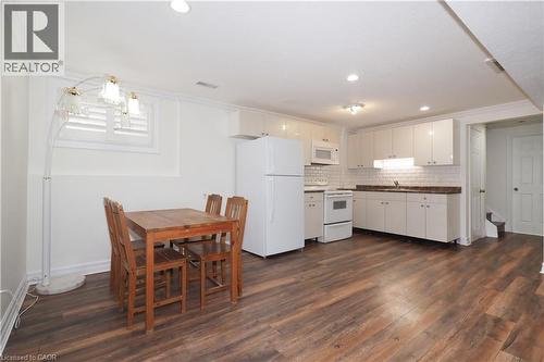 Open-concept kitchen and dining area featuring wood-finish flooring, white cabinetry, integrated appliances, a subway tile backsplash, and recessed lighting - 67 Hollyridge Crescent Unit# Lower, Kitchener, ON - Indoor