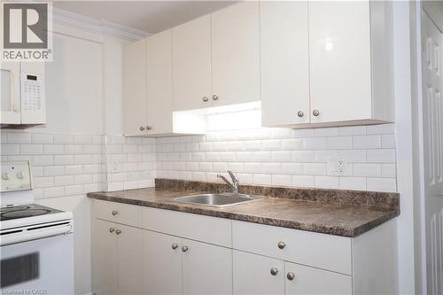 Kitchen featuring white cabinetry with silver hardware, under-cabinet lighting, a subway tile backsplash, and dark stone-finish countertops - 67 Hollyridge Crescent Unit# Lower, Kitchener, ON - Indoor Photo Showing Kitchen