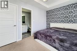 Bedroom featuring a decorative accent wall, tray ceiling, and carpet flooring - 