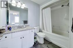 Bathroom featuring a white vanity with a speckled countertop, a built-in sink, and a large wall-mounted mirror - 