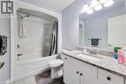 Bathroom featuring a white vanity with a granite-style countertop, undermount sink, and chrome faucet - 