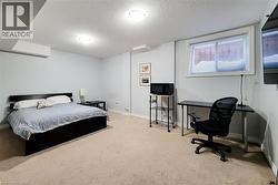 Carpeted room with light grey walls, featuring a window with horizontal blinds, recessed lighting, and a ceiling-mounted fixture - 