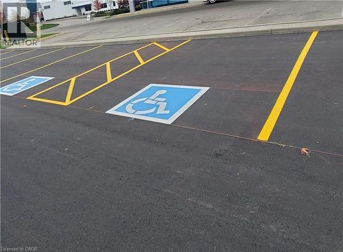 Paved parking lot featuring designated accessible parking spaces with blue and white markings, bright yellow striping, and a concrete curb - 44 Ditton Drive Unit# 3, Hamilton, ON 