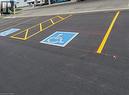 Paved parking lot featuring designated accessible parking spaces with blue and white markings, bright yellow striping, and a concrete curb - 44 Ditton Drive Unit# 3, Hamilton, ON 