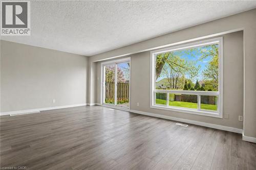 Spacious interior featuring wood-finish flooring, a large picture window, and sliding glass doors - 104 Ralgreen Crescent, Kitchener, ON - Indoor