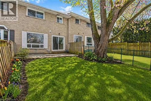 Expansive backyard featuring a manicured lawn, a mature deciduous tree, and a stone patio - 104 Ralgreen Crescent, Kitchener, ON - Outdoor