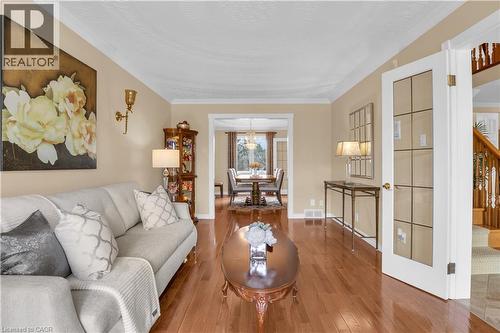 Living room featuring wood-finish flooring, crown molding, and an open entryway to the dining area - 228 Michener Crescent, Kitchener, ON - Indoor Photo Showing Living Room
