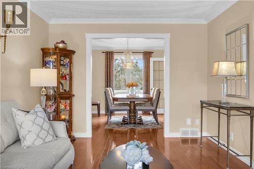 Polished wood-finish flooring extends through an open doorway into a dining area featuring a chandelier - 228 Michener Crescent, Kitchener, ON - Indoor Photo Showing Living Room