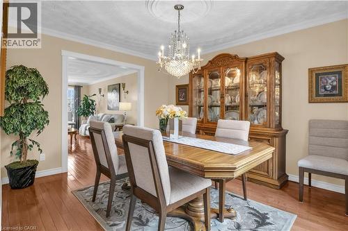 Dining area featuring hardwood flooring, crown molding, a decorative ceiling medallion, and an elegant crystal chandelier - 228 Michener Crescent, Kitchener, ON - Indoor Photo Showing Dining Room