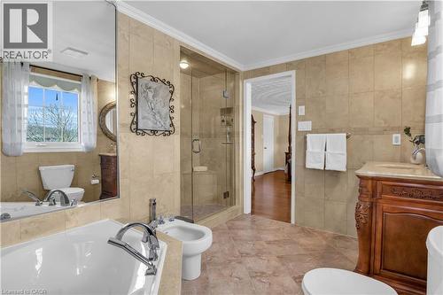 Spacious bathroom featuring tiled walls and flooring, a glass-enclosed shower with a built-in bench, a freestanding soaking tub with deck-mounted fixtures, and an ornate wood-finish vanity with a coun - 228 Michener Crescent, Kitchener, ON - Indoor Photo Showing Bathroom