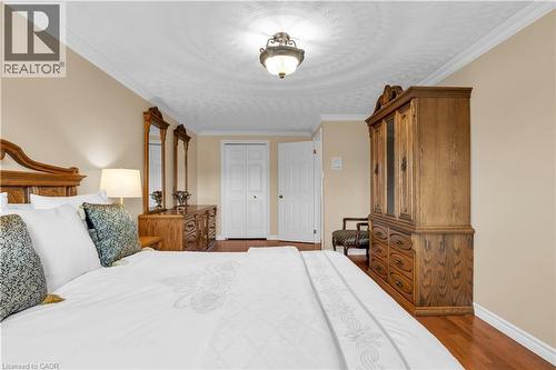Bedroom featuring crown molding, neutral wall color, wood-finish flooring, a ceiling-mounted light fixture, and white bi-fold closet doors - 228 Michener Crescent, Kitchener, ON - Indoor Photo Showing Bedroom