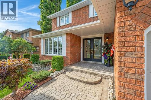 Brick exterior featuring a bay window with white shutters, a paver stone walkway, and a covered entry with double front doors - 228 Michener Crescent, Kitchener, ON - Outdoor
