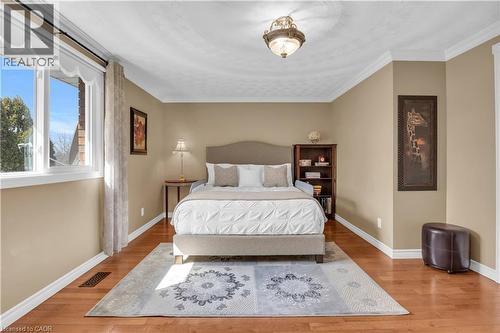 Spacious room featuring wood-finish flooring, ample natural light from a large window, crown molding, and a built-in ceiling fixture - 228 Michener Crescent, Kitchener, ON - Indoor Photo Showing Bedroom