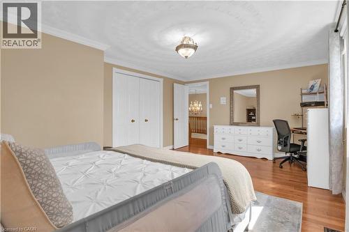 Spacious room featuring wood-finish flooring, neutral-toned walls, crown molding, and a double-door closet with gold-finish hardware - 228 Michener Crescent, Kitchener, ON - Indoor Photo Showing Bedroom