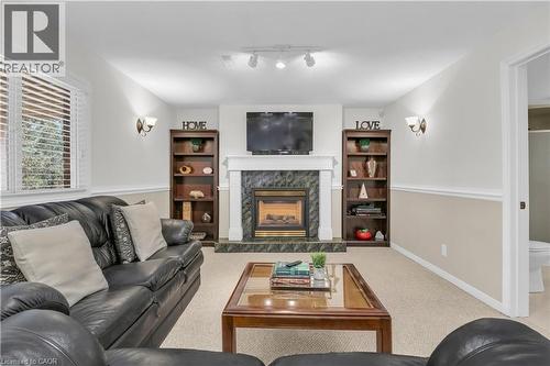 Carpeted living area featuring a fireplace with a dark green tile surround and white mantel - 228 Michener Crescent, Kitchener, ON - Indoor Photo Showing Living Room With Fireplace