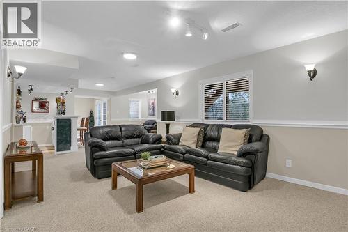 Spacious recreation room featuring neutral carpeting and a built-in bar with a stone-finish countertop - 228 Michener Crescent, Kitchener, ON - Indoor Photo Showing Living Room