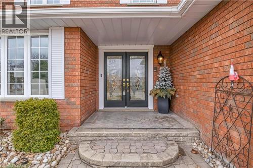 Brick exterior with a covered entry, featuring double glass-insert doors, large grid windows, and a stone paver walkway with steps - 228 Michener Crescent, Kitchener, ON - Outdoor With Exterior