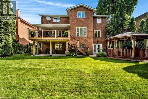 Expansive backyard featuring a manicured lawn, multi-level brick residence, an elevated wood-decked patio with protective railing, a secondary ground-level patio, and a detached wooden gazebo with dra - 228 Michener Crescent, Kitchener, ON - Outdoor With Deck Patio Veranda