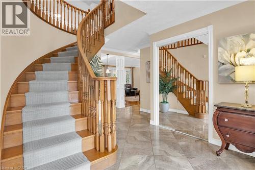 Grand hardwood spiral staircase featuring decorative balusters and light-toned carpet runner - 228 Michener Crescent, Kitchener, ON - Indoor Photo Showing Other Room