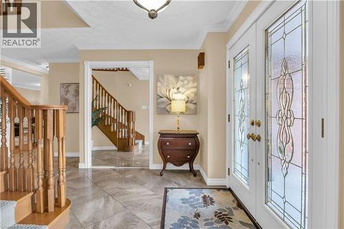 Entryway featuring double doors with decorative glass inserts, crown molding, a wood staircase with balusters, and large format tile flooring - 228 Michener Crescent, Kitchener, ON - Indoor Photo Showing Other Room