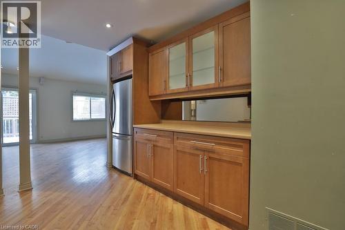 Built-in cabinetry featuring glass-front upper cabinets, a light wood-finish countertop, and integrated stainless steel refrigerator - 7 Gibson Place Unit# 21, St. Catharines, ON - Indoor