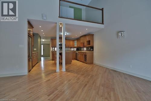 Open-concept interior featuring light wood-finish flooring throughout, a kitchen with wood cabinetry and stainless steel appliances, and a second-story overlook with a glass railing - 7 Gibson Place Unit# 21, St. Catharines, ON - Indoor