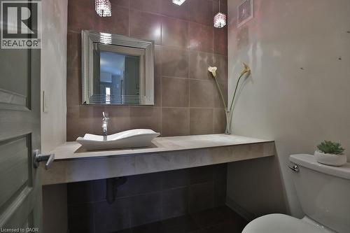 Bathroom featuring a vessel sink, chrome faucet, and a large framed mirror over a built-in vanity - 7 Gibson Place Unit# 21, St. Catharines, ON - Indoor Photo Showing Bathroom