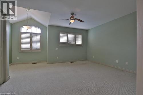 Carpeted room featuring a vaulted ceiling with a pendant light fixture, a second ceiling fan with integrated lighting, and two windows equipped with louvered shutters - 7 Gibson Place Unit# 21, St. Catharines, ON - Indoor Photo Showing Other Room