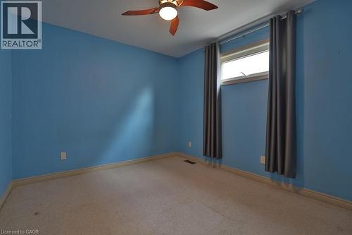 Carpeted room featuring a ceiling fan with integrated lighting, a window with a white frame, and blue painted walls - 7 Gibson Place Unit# 21, St. Catharines, ON - Indoor Photo Showing Other Room