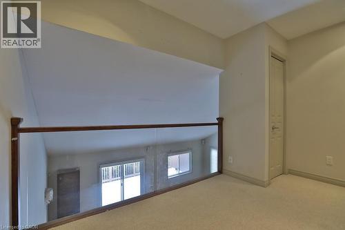 Carpeted loft area featuring a clear glass and wood railing overlooking the lower level - 7 Gibson Place Unit# 21, St. Catharines, ON - Indoor Photo Showing Other Room