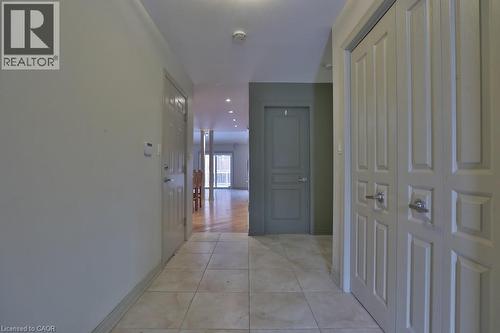 Hallway featuring tile flooring, paneled doors, recessed lighting, and a view into a room with wood-finish flooring and a balcony - 7 Gibson Place Unit# 21, St. Catharines, ON - Indoor Photo Showing Other Room