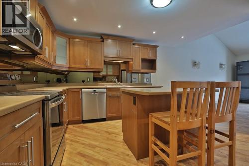 Kitchen featuring wood-finish flooring, light wood cabinetry, stainless steel appliances, and an integrated island - 7 Gibson Place Unit# 21, St. Catharines, ON - Indoor Photo Showing Kitchen