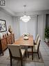 Dining area featuring a contemporary tiered chandelier, ceramic tile flooring, and a built-in wooden sideboard with cross-detail doors. Virtually staged. - 569 Activa Avenue, Kitchener, ON  - Indoor Photo Showing Dining Room 