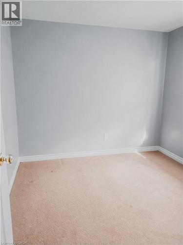Neutral-toned carpeting extends across the floor, complemented by light gray wall paint and white baseboards - 569 Activa Avenue, Kitchener, ON - Indoor Photo Showing Other Room