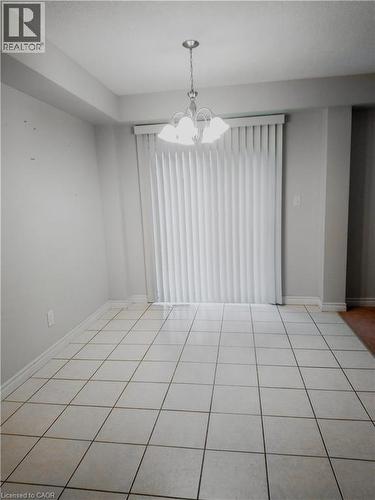Tiled flooring throughout this open space, featuring a chandelier and vertical blinds covering a large window - 569 Activa Avenue, Kitchener, ON - Indoor Photo Showing Other Room
